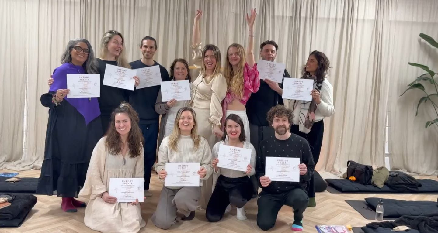 A group of Embody Shakti graduates holding up their certificates together at the end of a training with Maia
